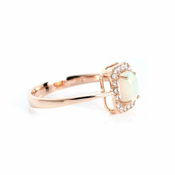 Rose gold ring with a pale cabochon gemstone surrounded by a diamond halo.